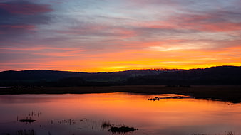 Vibrant Sunset Reflection Over Calm Lake and Marsh