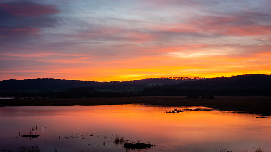 Vibrant Sunset Reflection Over Calm Lake and Marsh