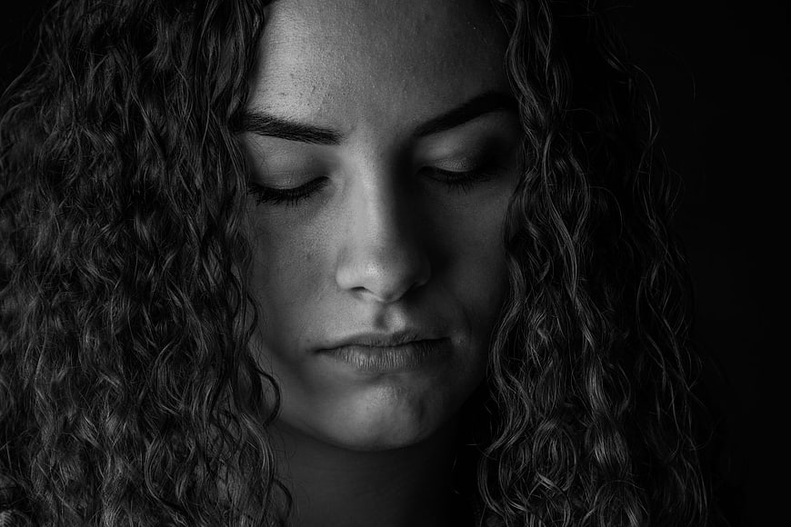 Black and white portrait of a woman with curly hair looking down