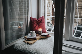 Cozy window seat with candle, coffee, and book