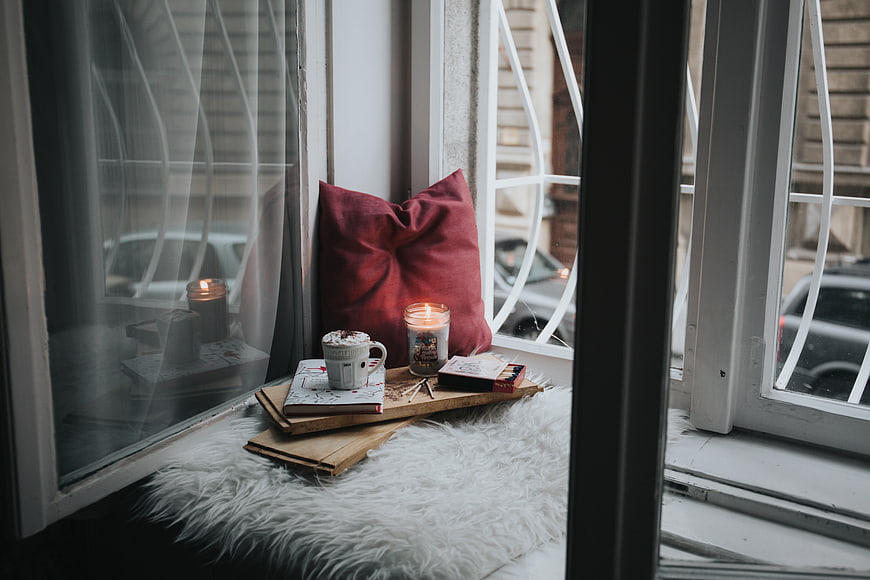 Cozy window seat with candle, coffee, and book