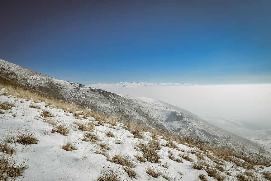 Snowy mountain slope with sea of clouds below
