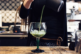 Barista pouring green matcha drink into glass with ice