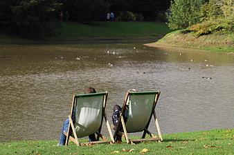 Couple relaxing in deckchairs by a lake with ducks