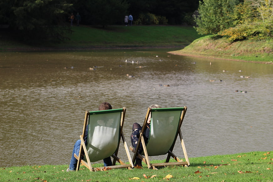 Couple relaxing in deckchairs by a lake with ducks