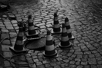 Black and white traffic cones on cobblestone street