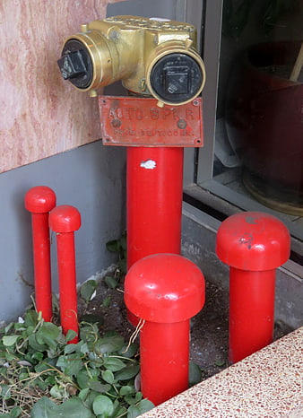 Red fire sprinkler standpipe with brass valve and protective bollards