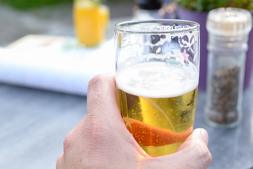 Hand holding a glass of cold beer with foam