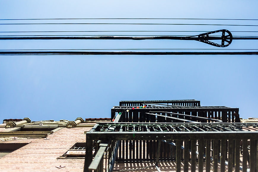 Urban rooftop architecture with power lines against blue sky