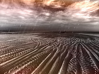 Dramatic desert landscape with tire tracks and rain under stormy sky