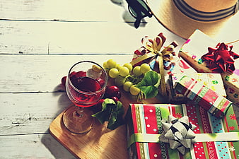 Christmas gifts, red wine, and grapes on rustic white wood