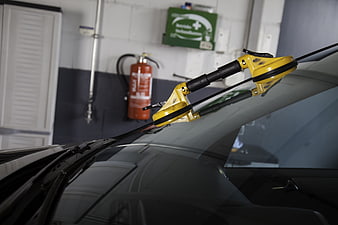 Yellow windshield replacement tool on car in auto repair shop