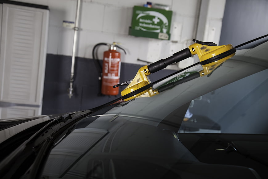 Yellow windshield replacement tool on car in auto repair shop