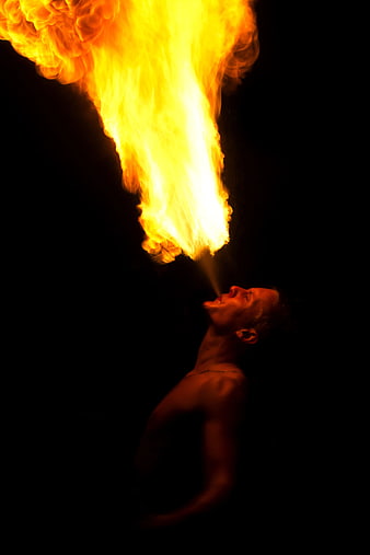 Man Breathing Fire Against Black Background