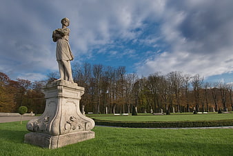 Classical statue in a manicured park with autumn trees