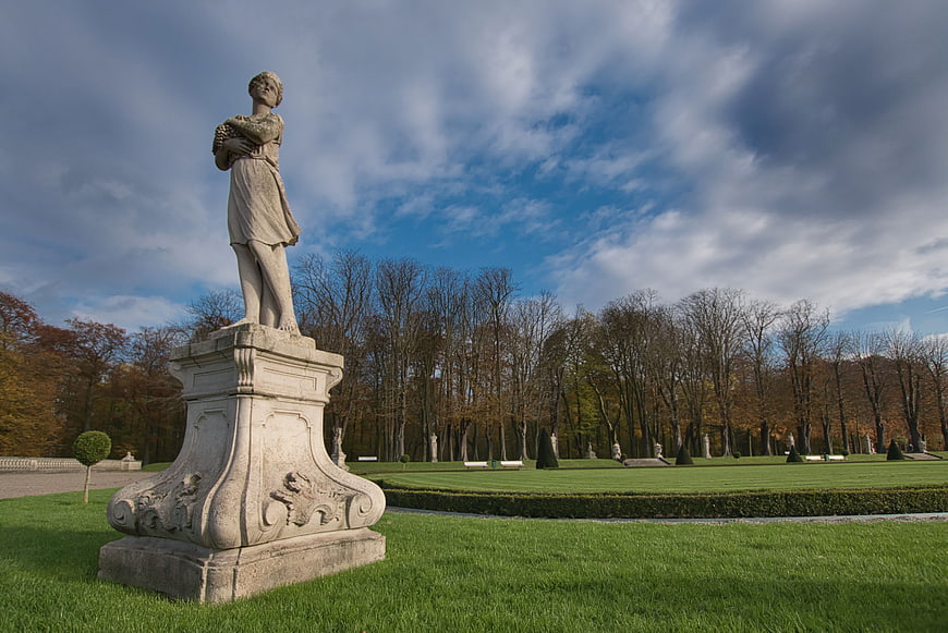 Classical statue in a manicured park with autumn trees