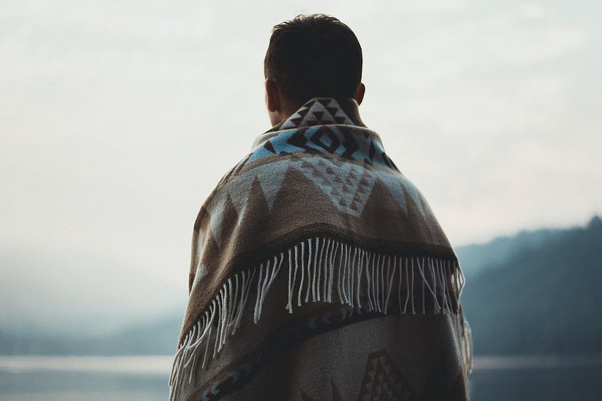 Man Wrapped in Patterned Blanket Looking at Lake
