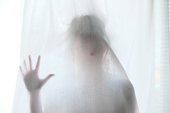 Silhouette of a person behind a sheer white curtain