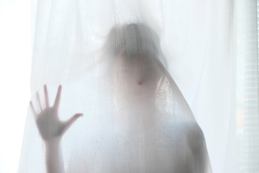 Silhouette of a person behind a sheer white curtain