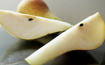 Close-up of fresh pear slices on a dark reflective surface