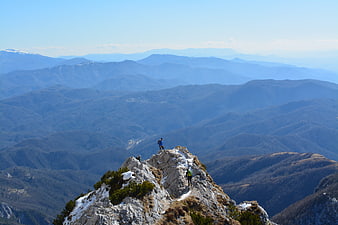 Hikers on Rocky Mountain Summit With Vast Valley Landscape