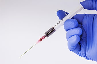 Gloved Hand Holding Syringe with Blood on White Background