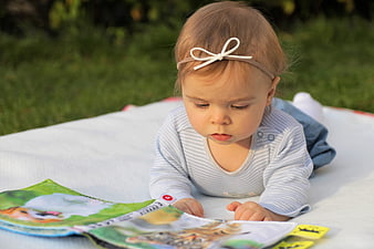 Baby Girl Reading Book on Blanket Outdoors