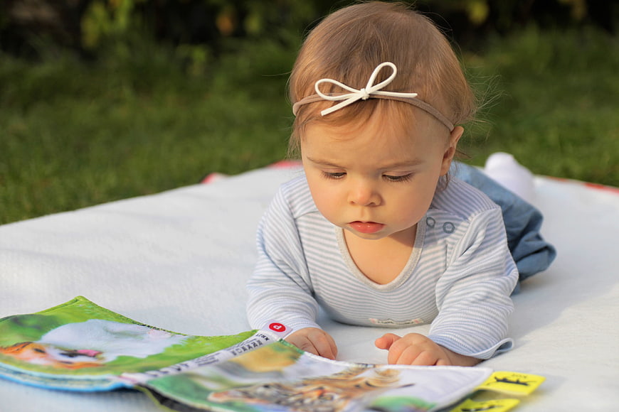 Baby Girl Reading Book on Blanket Outdoors