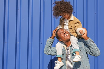 Happy Father Carrying Daughter on Shoulders Against Blue Wall
