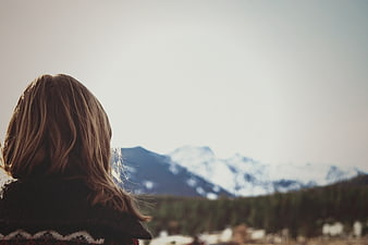 Woman with long hair looking at snowy mountains