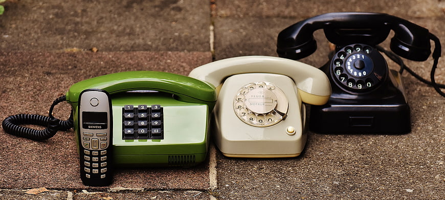 Vintage and Modern Telephones on Stone Pavement