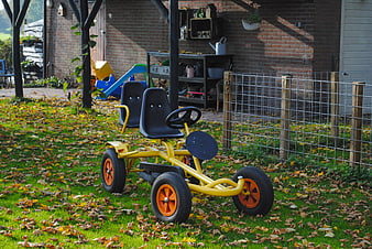 Yellow Go-Kart in Autumn Garden with Fallen Leaves