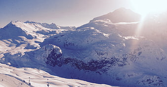 Snowy Mountain Peaks with Ski Lifts and Sun Flare
