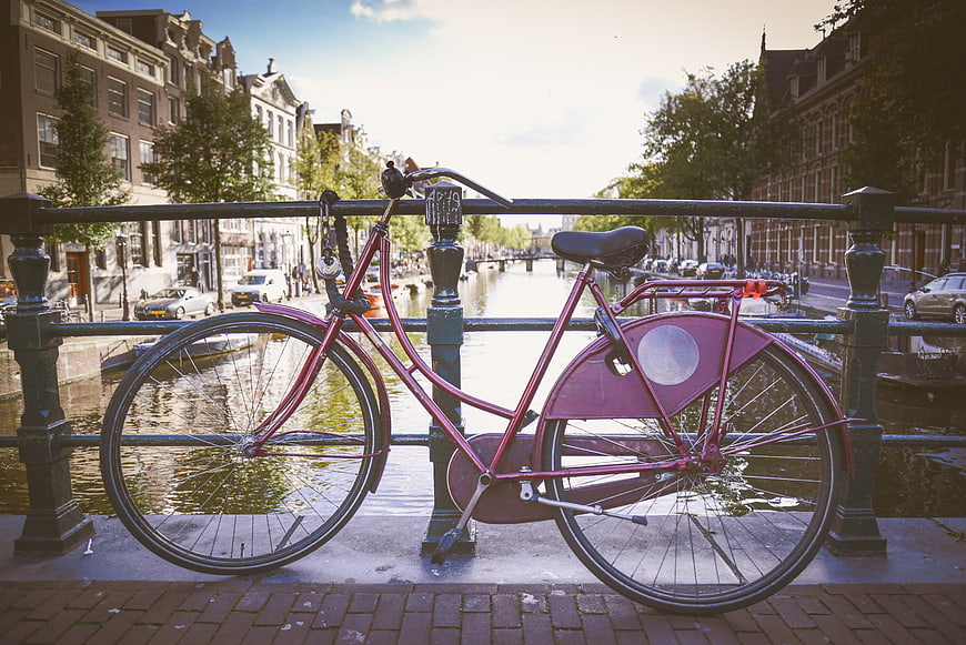Pink Bicycle Parked on Amsterdam Canal Bridge