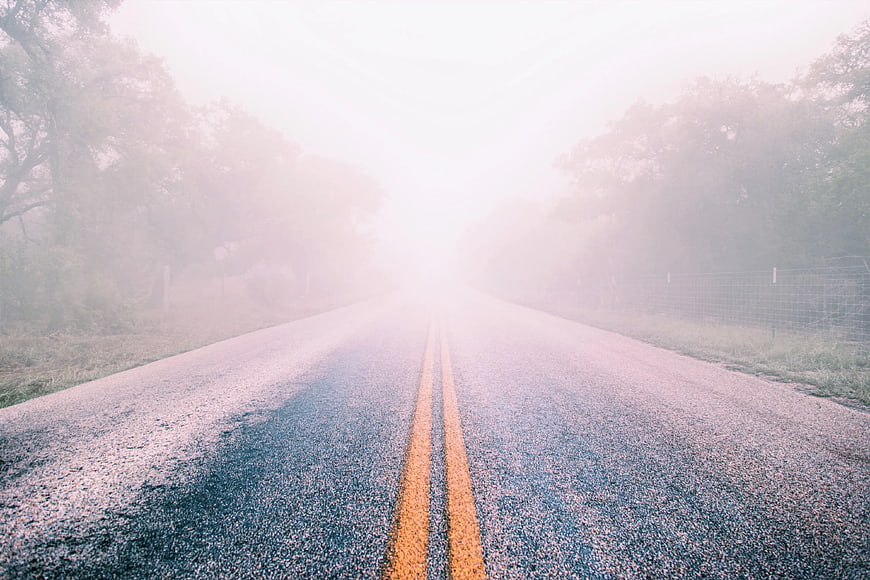 Foggy country road with double yellow lines and trees