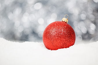 Red Glitter Christmas Ornament in Snow with Bokeh Background