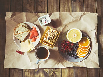 Healthy breakfast spread with coffee, fruit, and cheese on wood