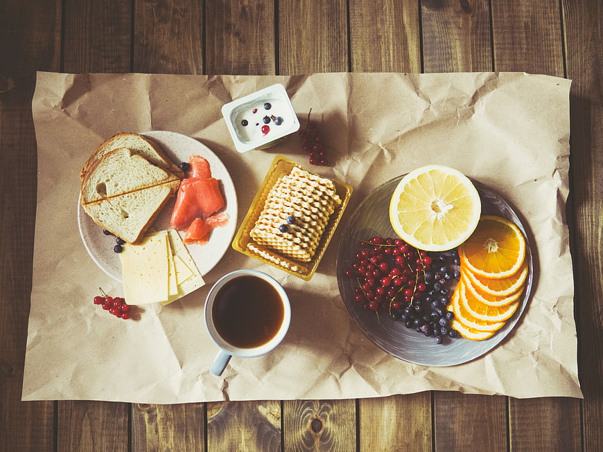 Healthy breakfast spread with coffee, fruit, and cheese on wood