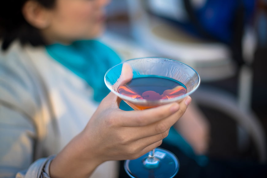 Hand holding colorful cocktail glass outdoors