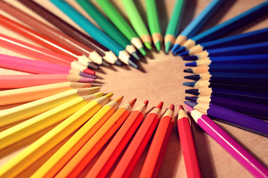 Rainbow colored pencils arranged in a circle on wood