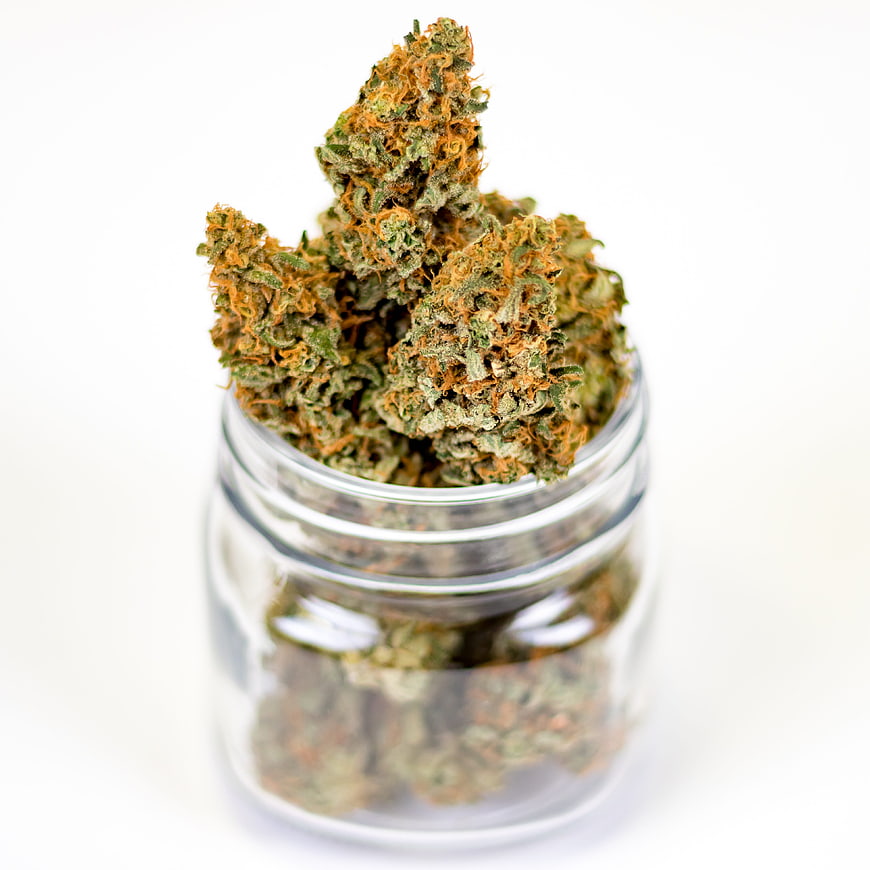 Cannabis buds in a clear glass jar on a white background