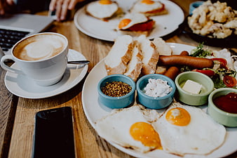 Hearty English breakfast with coffee and smartphone on wooden table