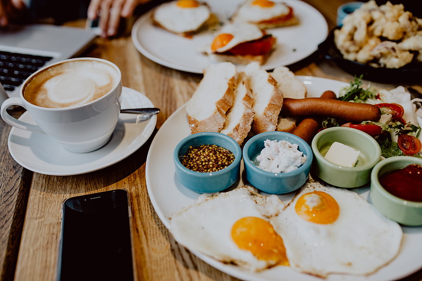 Hearty English breakfast with coffee and smartphone on wooden table