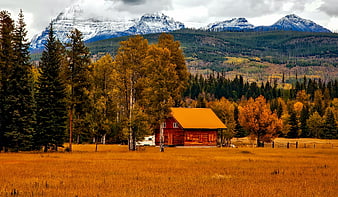 Red Log Cabin In Autumn Meadow With Snowy Mountains