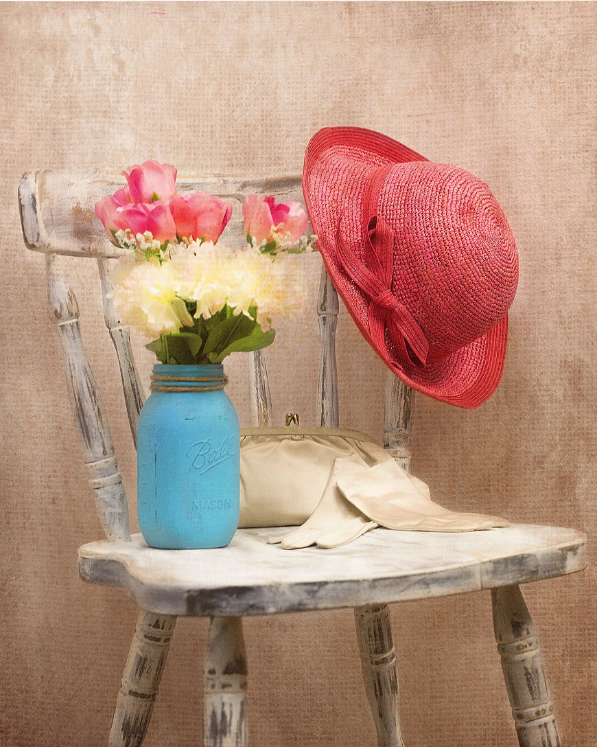 Vintage red straw hat and flowers on rustic chair