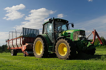 Green John Deere Tractor Pulling Hay Trailer in Pasture