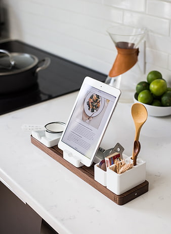 Kitchen counter with tablet displaying recipe and wooden utensil organizer