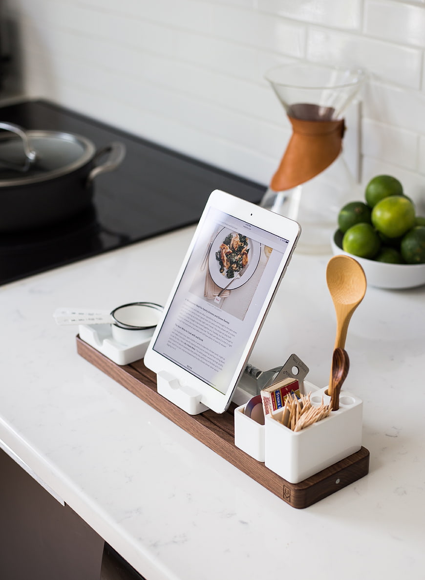 Kitchen counter with tablet displaying recipe and wooden utensil organizer