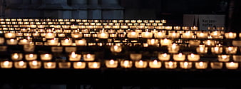 Rows of lit prayer candles in a dark church interior