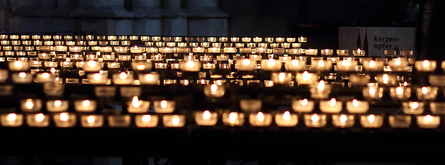Rows of lit prayer candles in a dark church interior